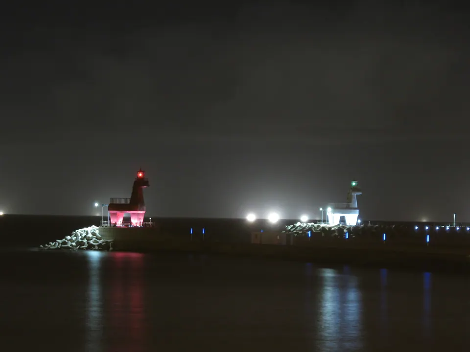 梨湖木筏海岸的夜景,紅色與白色馬形燈塔的燈光倒映在海面上
